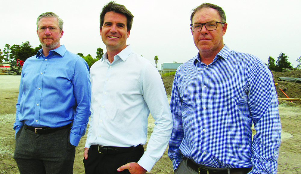 Three men standing at a construction site